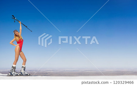 Attractive happy woman model in red swimsuit with skis on ski slope. 120329466