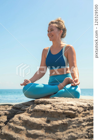 Yoga woman sitting in lotus position namaste hands cliff rock beach sea blue sky 120329500
