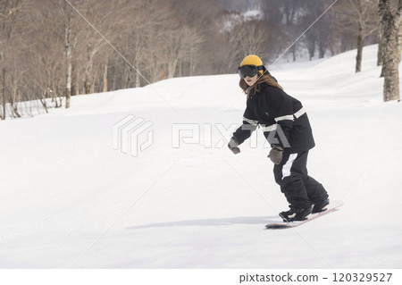 Young woman snowboarding down the slopes 120329527