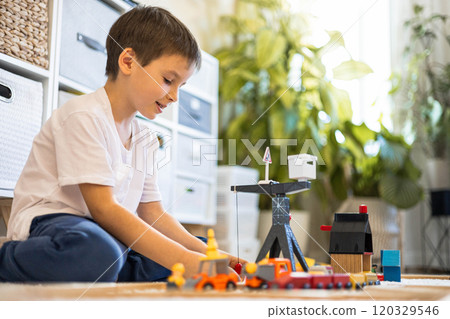 A cute little European boy builds a city and a railroad from wooden blocks. He plays with trains 120329546