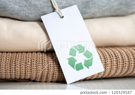 Stack of knitted clothes in neutral tones made of natural materials lies on table Stack of knitted clothes in neutral tones made of natural materials lies on table 120329587