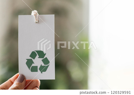 Hand takes a label with the inscription 100 percent recycled material. Recyclable product concept. Hand takes a label with the inscription 100 percent recycled material. Recyclable product concept. 120329591