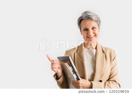 A middle-aged European woman with gray hair is dressed in a formal beige jacket and glasses.  120329659