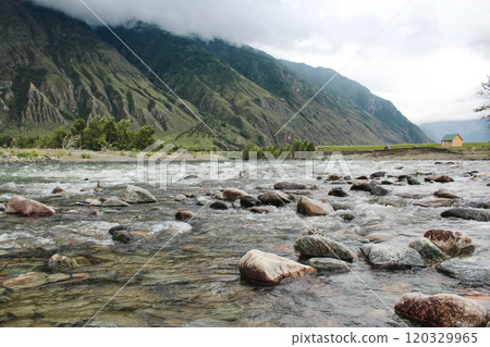 House on the banks of fast river Chulyshman, in Altai mountains. Stones in water, green trees. Tourist recreation center 120329965