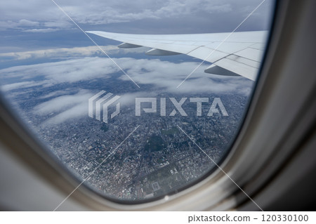 Gaze out of an airplane window to witness the harmonious blend of the airplane wing against the backdrop of the city and sky. Gaze out of an airplane window to witness the harmonious blend of the airplane wing against the backdrop of the city and sky. 120330100