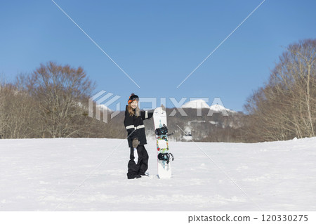 一名年輕女子站在滑雪板上看著相機滑雪板圖像 120330275