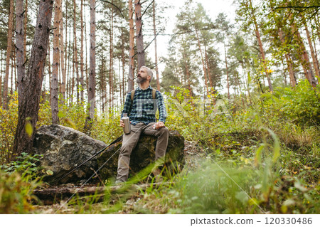 Handsome man standing in the middle of nature, enjoying peaceful atmosphere of the forest, forestbathing. 120330486