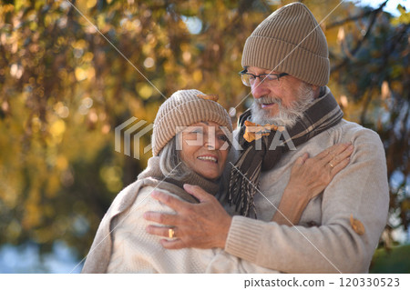 Portrait of beautiful senior couple during walk in autumn park. Elderly husband and wife are embracing each other. 120330523