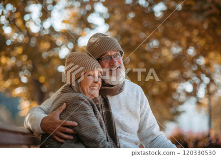 Portrait of beautiful senior couple during walk in autumn park. Elderly husband and wife are embracing each other. Portrait of beautiful senior couple during walk in autumn park. Elderly husband and wife are embracing each other. 120330530