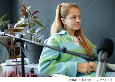 Side view portrait of blonde teenage girl with microphone recording podcast or interview as creative project for school, copy space 120331493