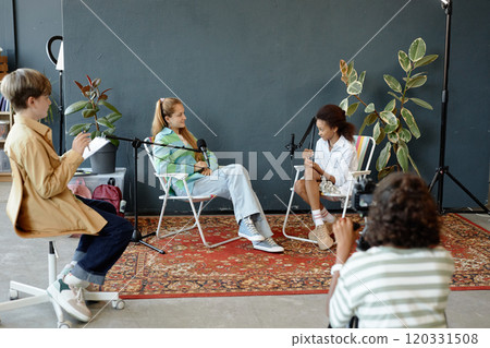 Backstage wide angle shot of group of teenage kids recording podcast or interview in studio and speaking to microphones, copy space 120331508