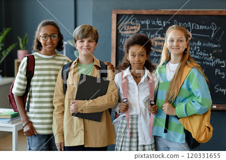 Multiethnic group of young children posing together standing in school classroom and looking at camera with smiles Multiethnic group of young children posing together standing in school classroom and looking at camera with smiles 120331655