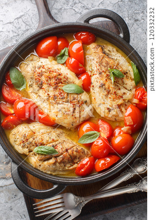 Delicious chicken fillet fried and then stewed with onions, garlic and tomatoes close-up in a frying pan on the table. Vertical top view Delicious chicken fillet fried and then stewed with onions, garlic and tomatoes close-up in a frying pan on the table. Vertical top view 120332232