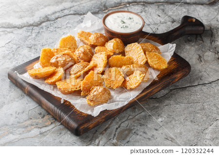 Crispy appetizer parmesan baby potatoes with sour cream dipping sauce close-up on parchment paper. Horizontal Crispy appetizer parmesan baby potatoes with sour cream dipping sauce close-up on parchment paper. Horizontal 120332244