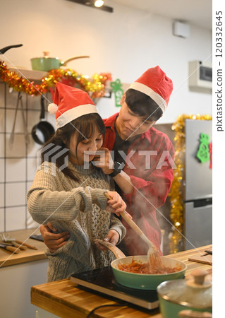 Affectionate couple enjoys cooking together in the kitchen decorated with Christmas ornaments Affectionate couple enjoys cooking together in the kitchen decorated with Christmas ornaments 120332645