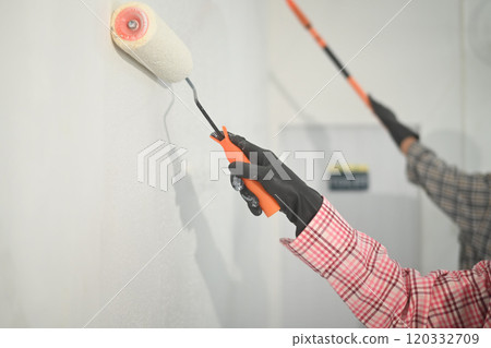 Close up of hands painting a wall with roller brushes 120332709