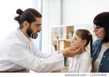 Doctor examining girl's lymph nodes while mother watches attentively Doctor examining girl's lymph nodes while mother watches attentively 120332909