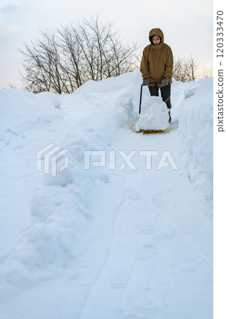 A young woman shoveling snow with a snow dump 120333470