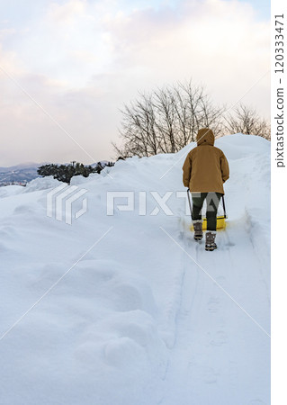 A young woman shoveling snow with a snow dump 120333471