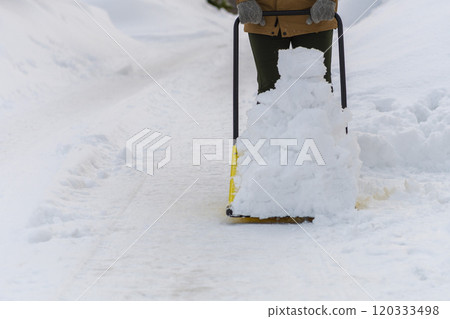 A young woman shoveling snow with a snow dump A young woman shoveling snow with a snow dump 120333498