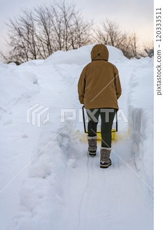 A young woman shoveling snow with a snow dump A young woman shoveling snow with a snow dump 120333511