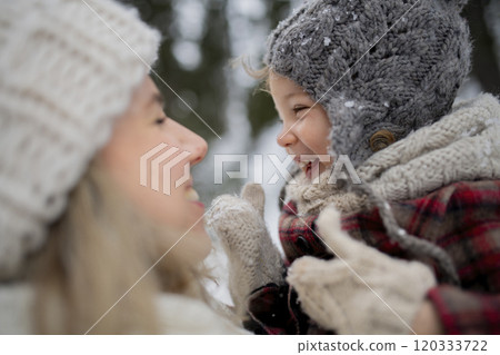 Mother standing in the middle of snowy landscape holding daughter in arms. Mom and girl enjoying winter holiday in the mountains. Mother standing in the middle of snowy landscape holding daughter in arms. Mom and girl enjoying winter holiday in the mountains. 120333722
