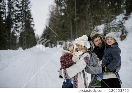 Young family is enjoying winter holiday in the mountains, standing in the middle of snowy forest. Young family is enjoying winter holiday in the mountains, standing in the middle of snowy forest. 120333723