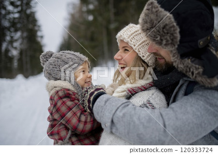 Young family is enjoying winter holiday in the mountains, standing in the middle of snowy forest. 120333724