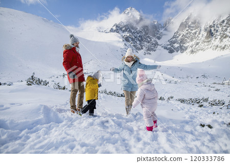 Young family is enjoying winter holiday in the mountains, playing in snow, having snowball fight. Young family is enjoying winter holiday in the mountains, playing in snow, having snowball fight. 120333786