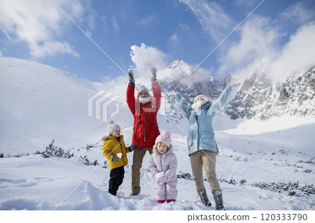 Young family is enjoying winter holiday in the mountains, standing in the middle of snowy landscape and throwing snow in the air . Young family is enjoying winter holiday in the mountains, standing in the middle of snowy landscape and throwing snow in the air . 120333790