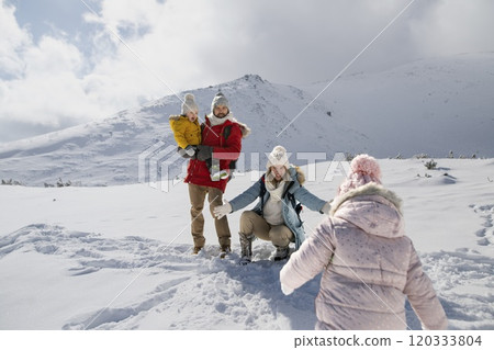 Young family is enjoying winter holiday in the mountains, playing in snow, having fun. 120333804