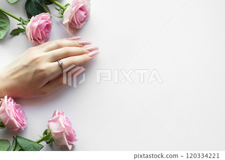 Woman hand showing stylish pink manicure with ring and pink roses on white background 120334221