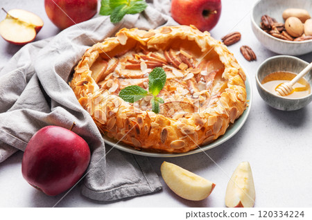 Delicious homemade apple galette with almond petals, honey, and fresh mint on grey table 120334224