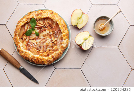 Delicious apple galette with honey and almond flakes on a tiled table Delicious apple galette with honey and almond flakes on a tiled table 120334225