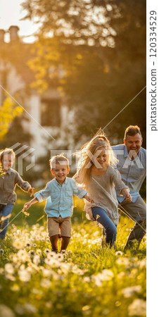 Happy family playing together in the garden. A young family spending time together outdoors in the yard Happy family playing together in the garden. A young family spending time together outdoors in the yard 120334529