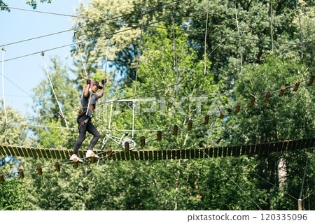 Experience an exhilarating high ropes course adventure nestled among vibrant and lush green trees all around Experience an exhilarating high ropes course adventure nestled among vibrant and lush green trees all around 120335096
