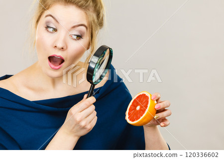 Woman holding magniferlooking grapefruit Woman holding magniferlooking grapefruit 120336602