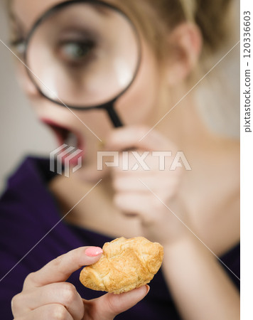 Woman holding magnifying glass investigating bread Woman holding magnifying glass investigating bread 120336603