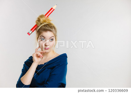 Thinking blonde woman having big pencil in hair 120336609