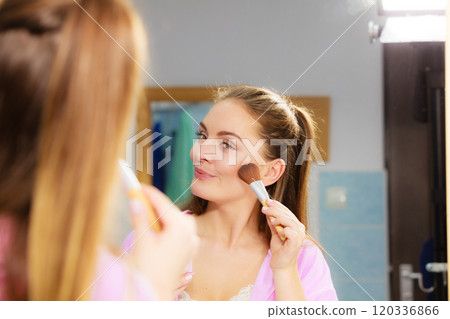 Woman applying bronzing powder with brush to her skin 120336866