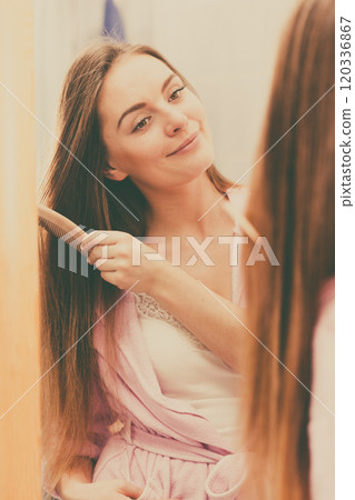 Woman combing her long hair in bathroom Woman combing her long hair in bathroom 120336867