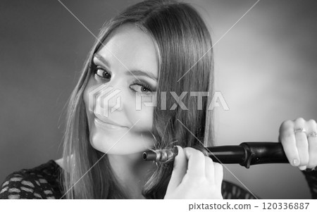 Happy woman curling her long brown hair Happy woman curling her long brown hair 120336887