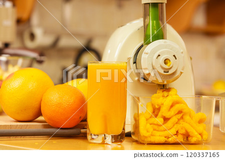 Making orange juice in juicer machine in kitchen 120337165