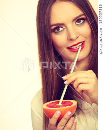 Woman holds grapefruit drinking juice from fruit Woman holds grapefruit drinking juice from fruit 120337316