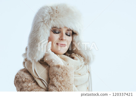 relaxed woman in winter coat and fur hat on white 120337421