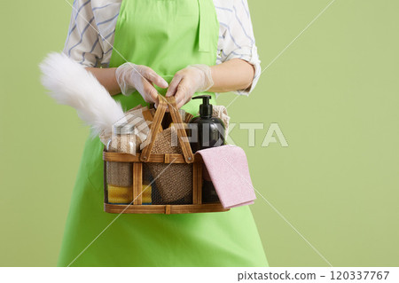 Modern housewife in green apron and rubber gloves against green 120337767