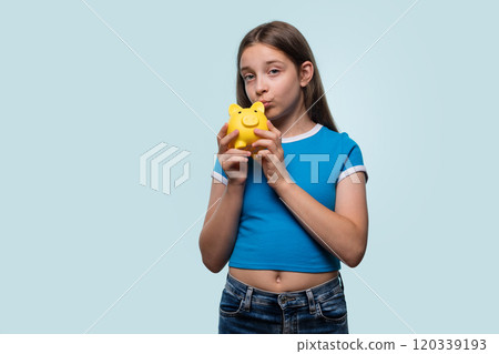 Girl kissing a yellow piggy bank Girl kissing a yellow piggy bank 120339193