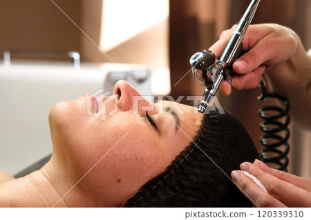 Aesthetician using airbrush machine to perform jet peeling Aesthetician using airbrush machine to perform jet peeling 120339310
