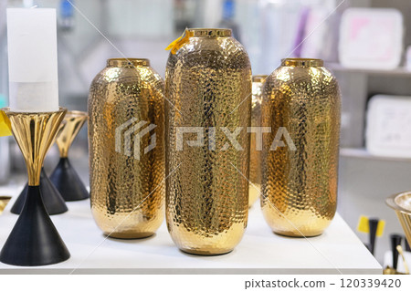 Golden vases are sold in shop. Jars for bouquets of flowers. Sale of items for decorating premises. Golden vases are sold in shop. Jars for bouquets of flowers. Sale of items for decorating premises. 120339420