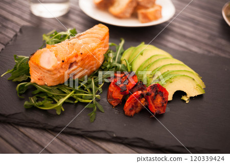 Baked sea trout fillet with fresh vegetables and herbs on black board Baked sea trout fillet with fresh vegetables and herbs on black board 120339424